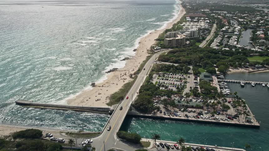 A stunning aerial pan from a mansion unveils a breathtaking inlet and Boynton Beach Florida with luxury homes lining the shore