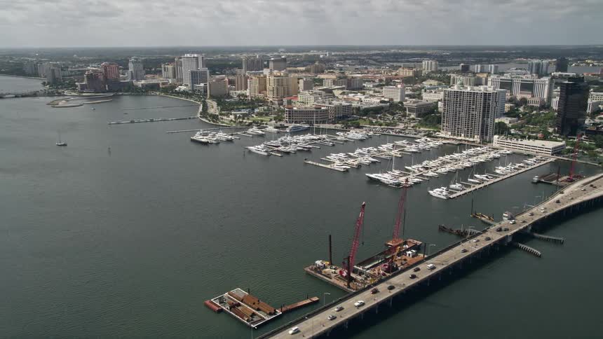 Approaching Flagler Memorial Bridge on Lake Worth Palm Beach Florida via aerial view with boats docked at Palm Harbor Marina below
