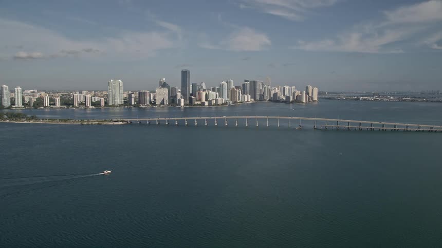 A stunning aerial view of Rickenbacker Causeway Downtown Miami and Biscayne Bay with towering high rises bridges and a bustling metropolis surrounded by sparkling water bodies and nature