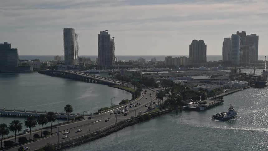 An aerial view of cars and trucks crossing the MacArthur Causeway as it leads into South Beach Miami with the sunny Florida shoreline in the distance