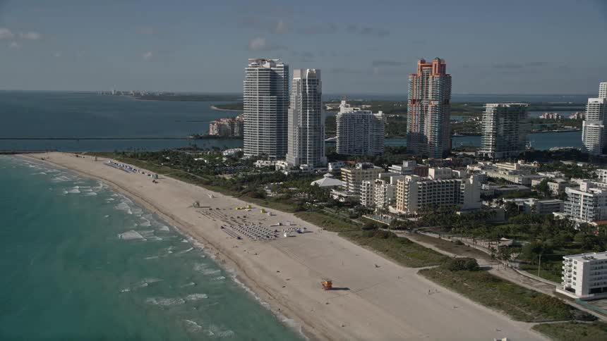 Flying above South Beach in Miami jumping over the shoreline and approaching the towering skyscrapers