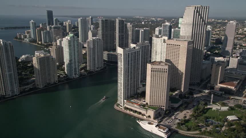 An aerial view of a bustling downtown city near the coastline showing Miami River reveal during midday in Florida