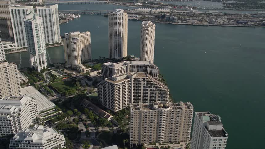 Fly over the luxurious Mandarin Oriental hotel towards the residential Brickell Key condos showcasing the metropoliss skyline in sunny Downtown Miami Florida
