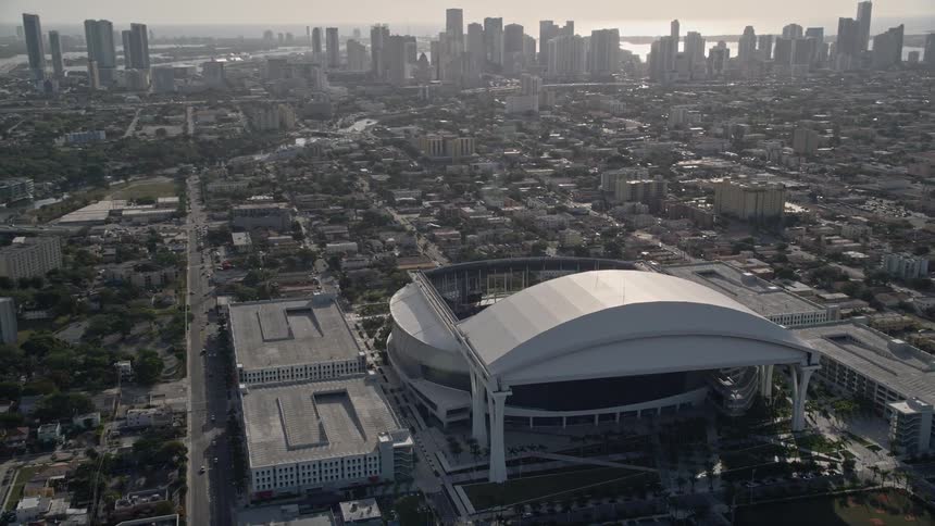 An aerial footage captures the impressive Marlins Park stadium and Downtown Miami skyline on a sunny day during a baseball game