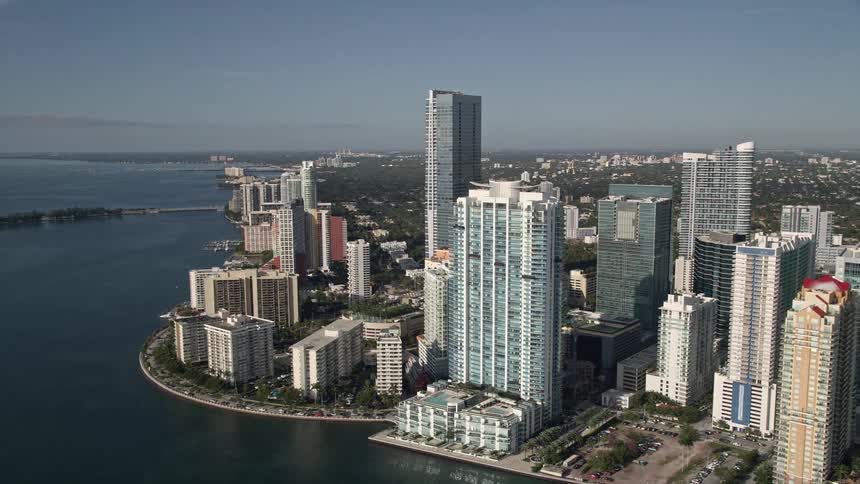 Flying over Mandarin Oriental on Brickell Key towards the towering skyscrapers and apartment buildings of Downtown Miami showcasing the stunning metropolis set against the Florida coastline