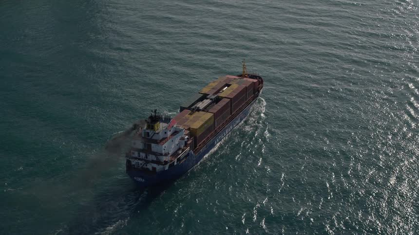 Approaching a cargo ship sailing on Government Cut in Miami Beach with the blue ocean and blue sky creating a beautiful backdrop as the ship sails into view
