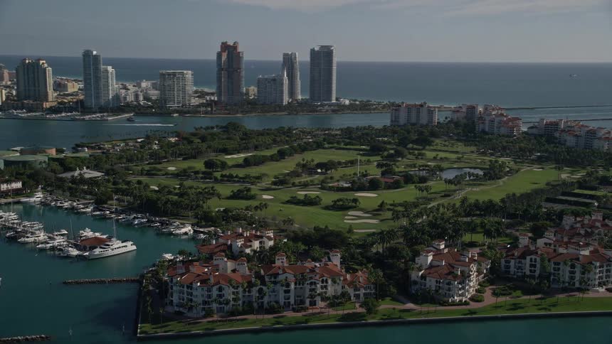 Aerial view of Fisher Island Golf Course and its surroundings including waterfront properties and city skyline in the background