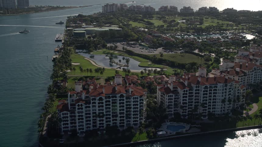 A stunning aerial shot of Fisher Island Florida featuring orbiting condominiums and townhouses situated along the coastline within a residential neighborhood