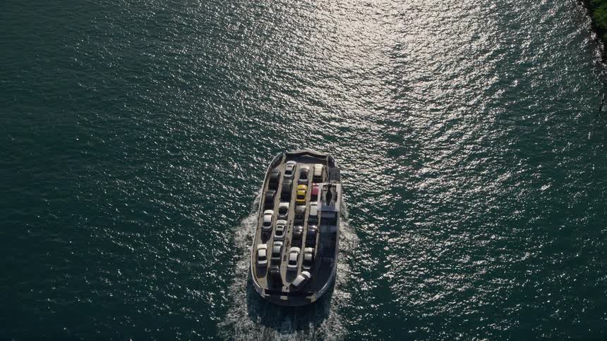 Approaching ferry sailing on Government Cut with a birds eye view tilting down towards Miami Beachs sunny atmosphere and vessels on the ocean transporting cars during the day
