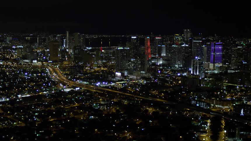 The aerial footage captures the stunning high-rise skyline of Downtown Miami at night showcasing a clear cityscape with towering buildings clear skies and a beautiful approach