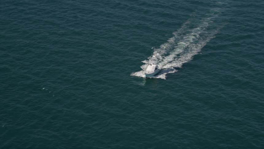 Aerial footage of a fishing boat moving on the Atlantic Ocean with Miamis beautiful coastline and an abundance of sunshine in the background