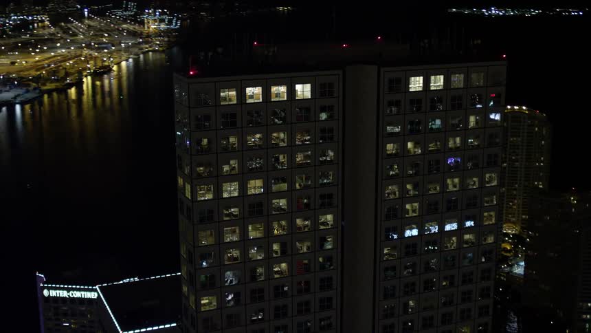 An aerial view of the illuminated Southeast Financial Center in Downtown Miami at night overlooking the sea