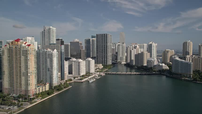Fly low over Biscayne Bay reveal skyscrapers and Brickell Key in Downtown Miami Florida