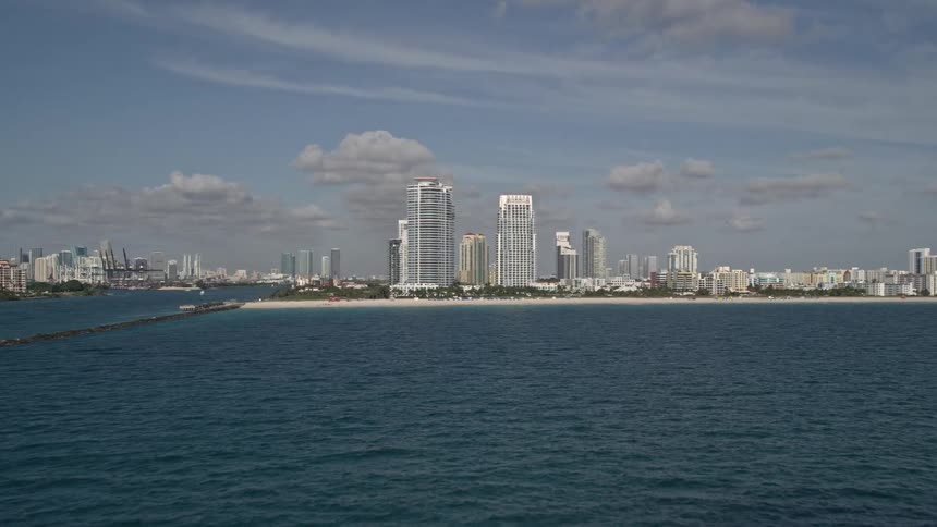 Aerial view of South Beachs skyscrapers and coastline as the camera approaches the city from the Atlantic Ocean in Florida