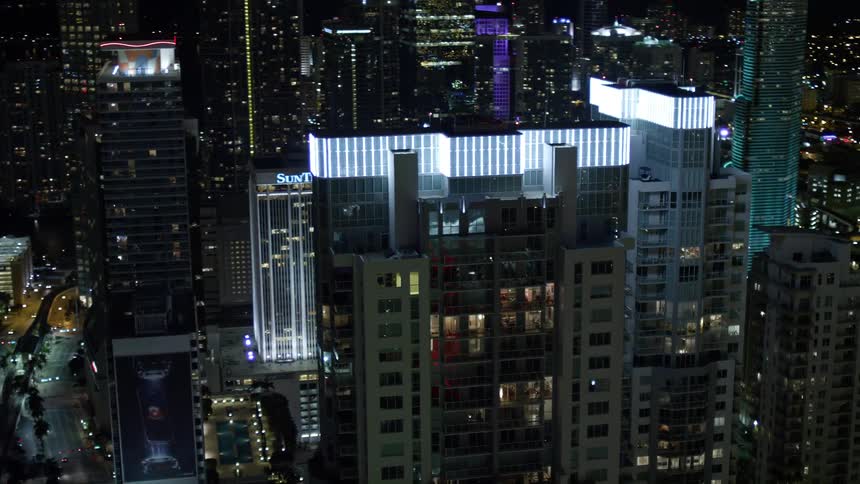 Stunning aerial footage of the brightly lit rooftops of the Vizcayne towers at night in downtown Miami showcasing the modern and sleek architecture of Southern Floridas metropolitan cityscape