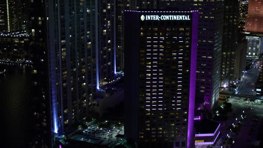 Tilt up from Bayside Marketplace to reveal the InterContinental buildings impressive night lights and illuminated image on the side in downtown Miami Florida