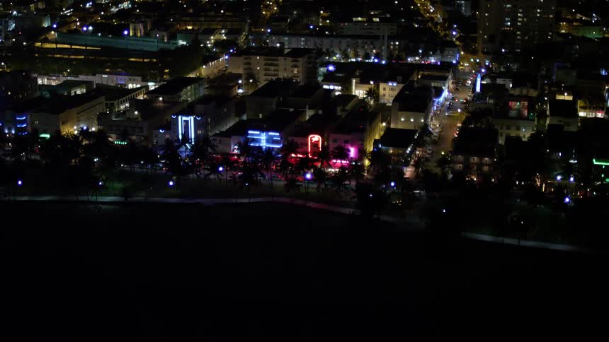 Aerial view of South Beachs hotels at night approached after panning from ocean