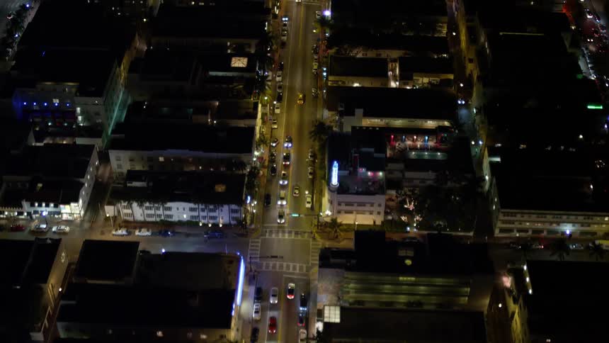 Aerial view of cars driving through South Beachs Collins Avenue at nighttime