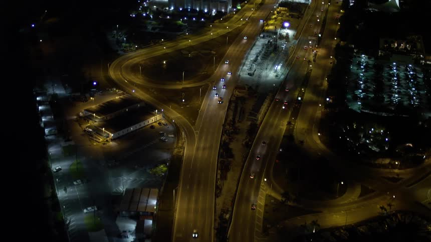 Aerial flyover of MacArthur Causeway traffic through Watson Island at night in Florida