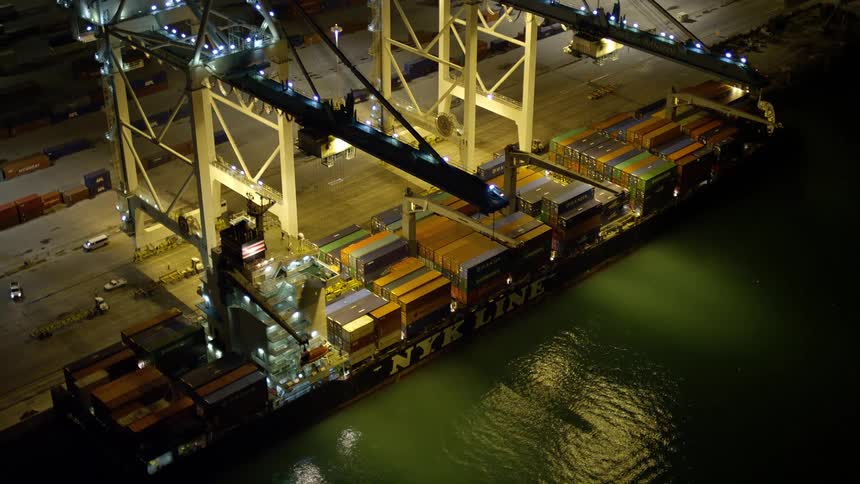 Two towering cranes expertly load a cargo ship under the clear night sky at the bustling Port of Miami