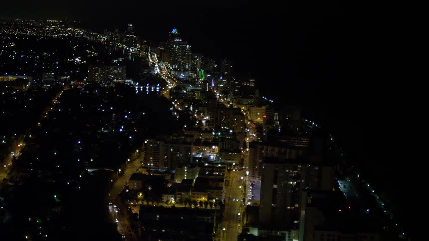 A stunning aerial footage of Miami Beachs bright and busy streets at nighttime showcasing the citys seaside charm and metropolitan atmosphere