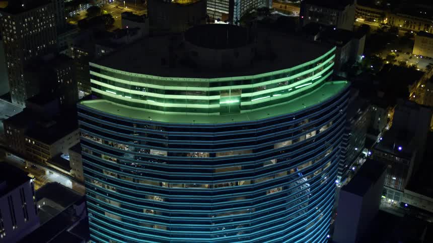 An aerial view of Miami Tower in downtown Miami at night showcasing the citys towering skyscrapers and metropolis in clear vivid detail