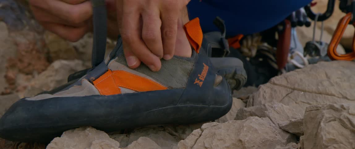 A hand reaches down and adjusts a walking shoe