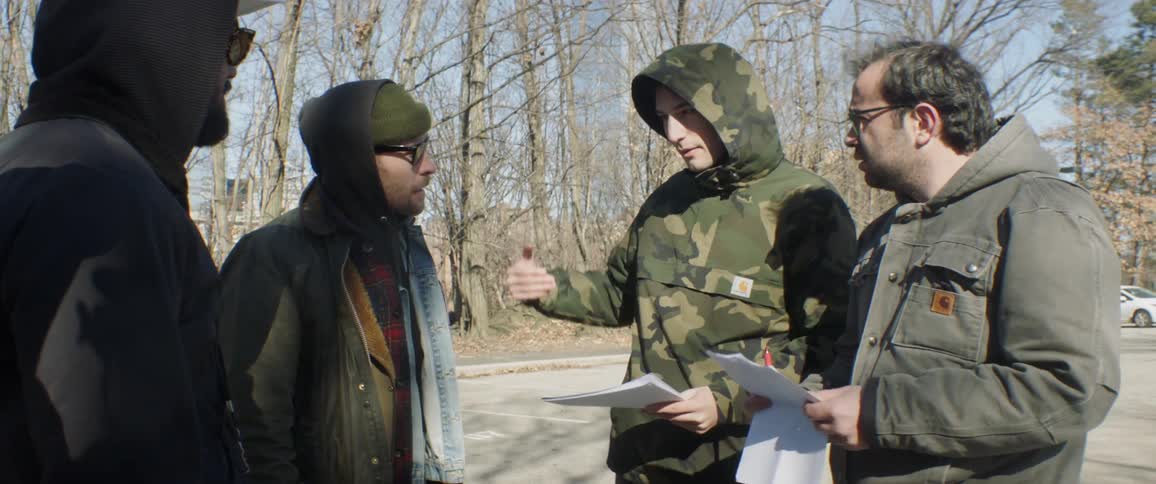 Film crew talks outside near the woods