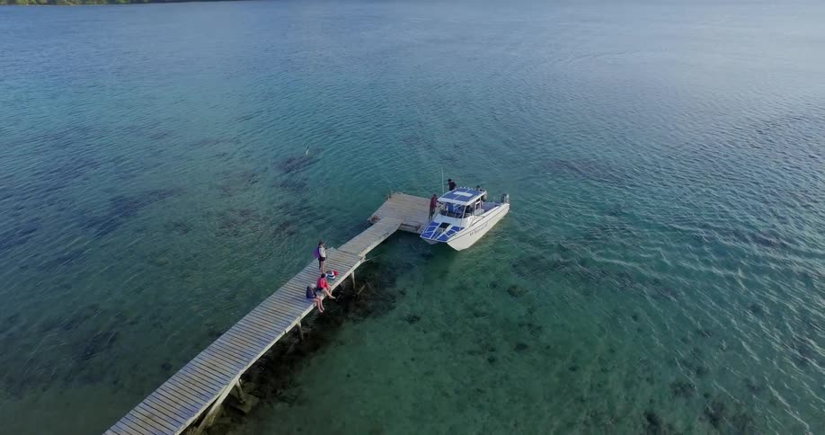 People stand on a dock while a boat is parked