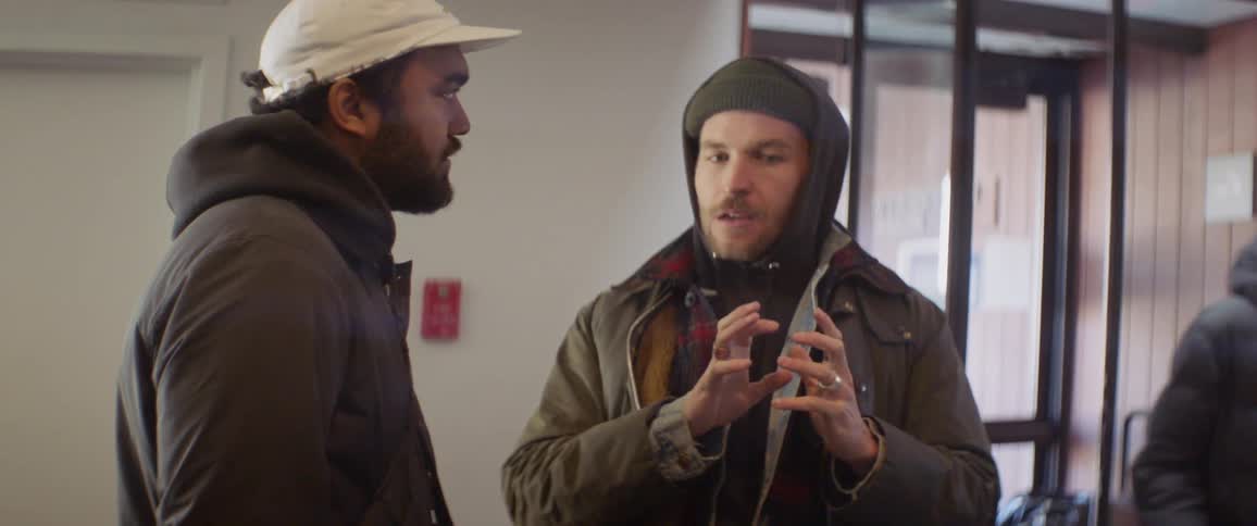 Two men talk near a building entrance