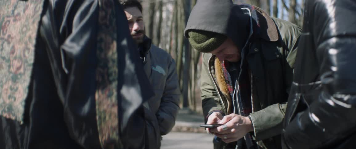 Man wearing a toque looks down and scrolls on his cellphone