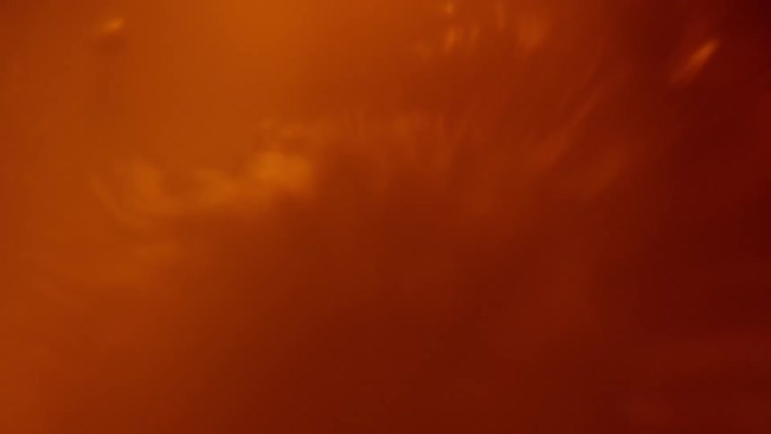 An orange liquid bubbles and sloshes around very vigorously
