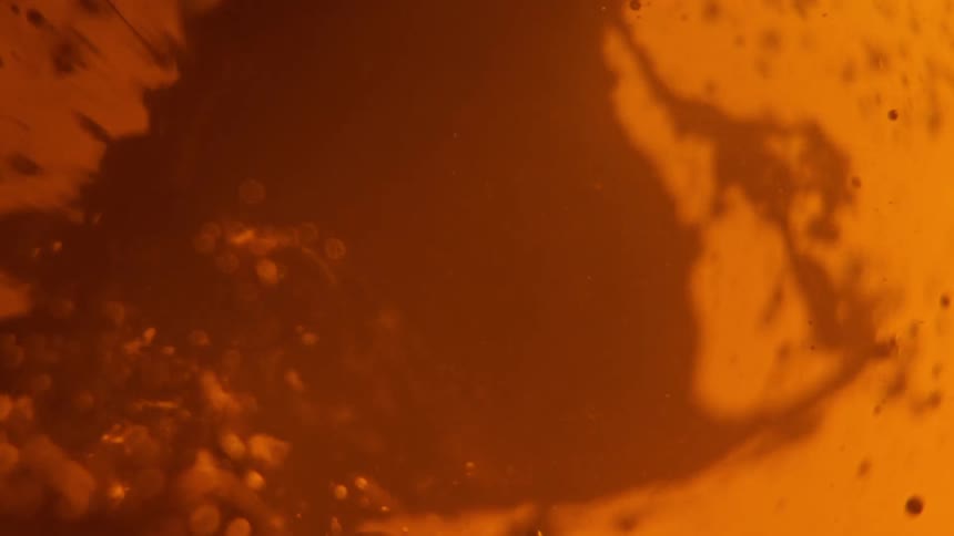 A dark orange liquid combines with a lighter orange liquid