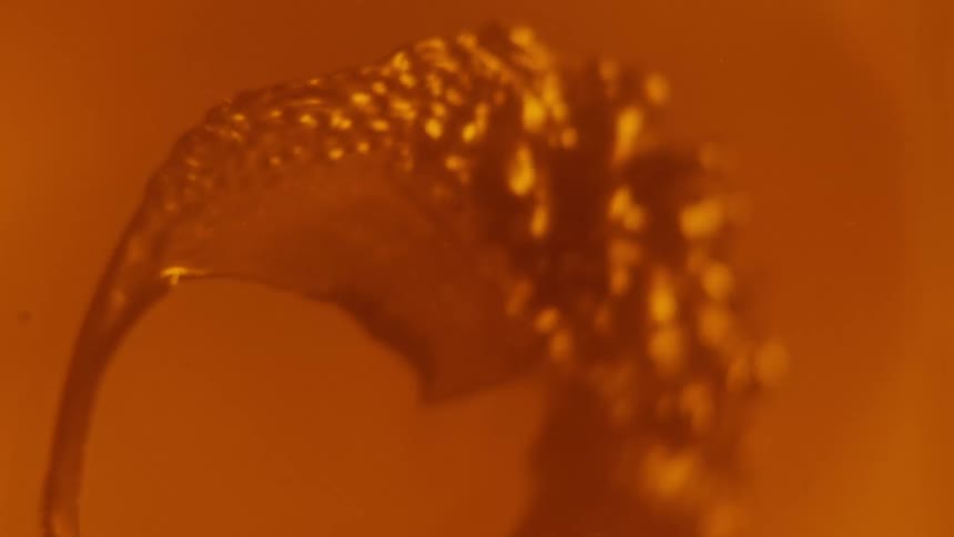 A viscous orange liquid spreads out and bubbles up