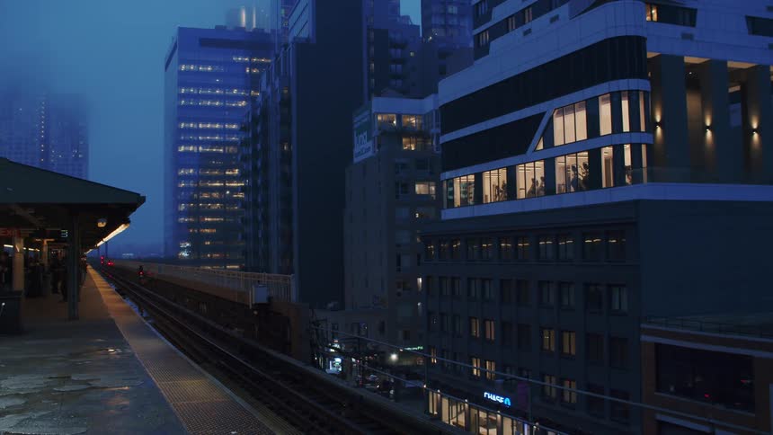 A row of tall buildings are seen nearby to some train tracks