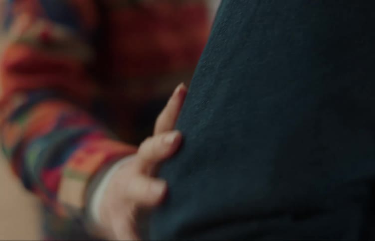 Woman strokes her hand down coat covered arm of second person