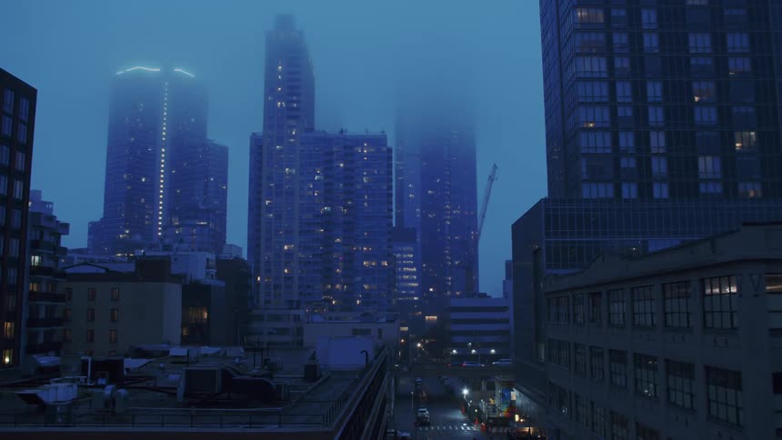 Pedestrian crosses intersection on road paralleling busy bridge in foggy downtown
