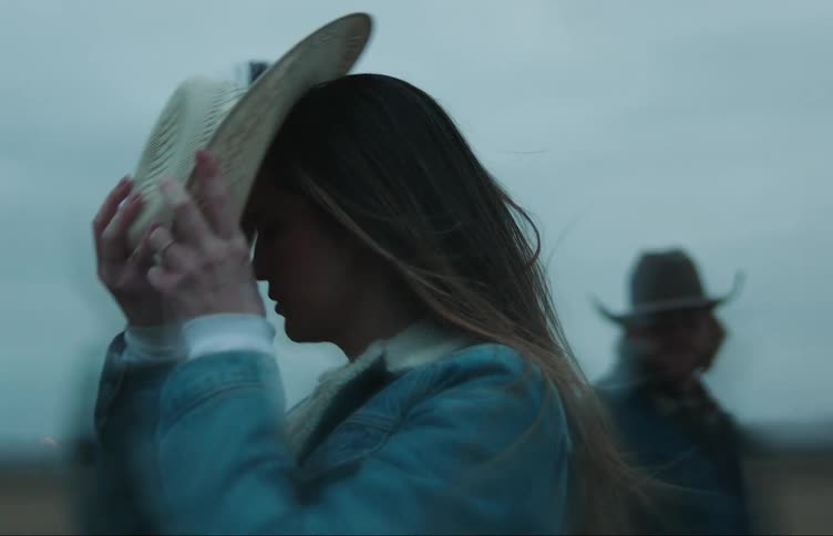 A woman puts on a cowboy hat
