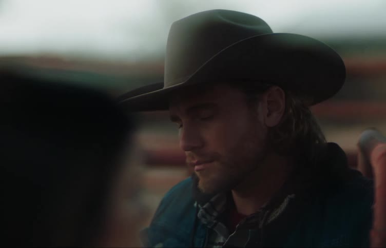 A man and woman turn to look at each other on a farm