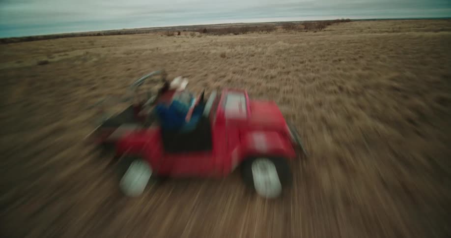 Two men ride an off road vehicle through an open field