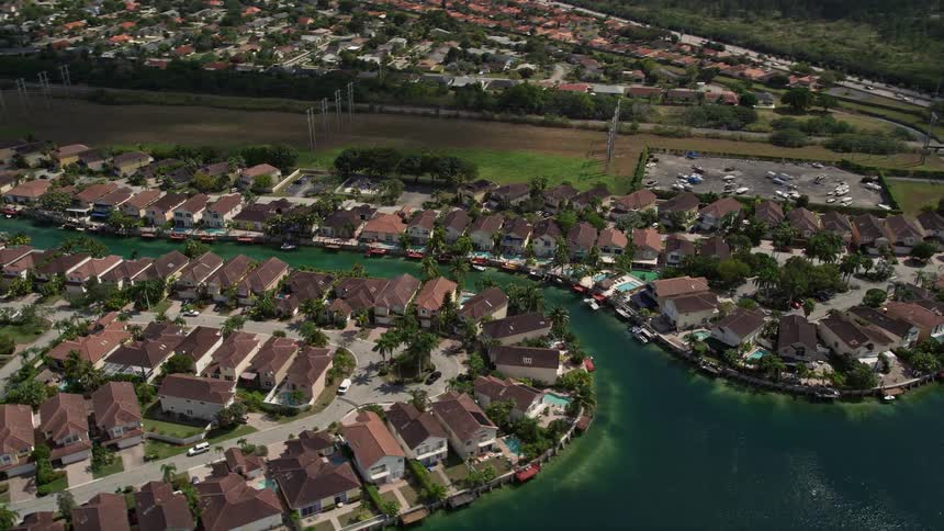 Flying over canal side homes in Three Lakes Miami Florida on a sunny day