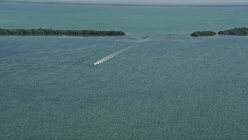 A speedboat cuts through the calm waters of Manatee Bay leaving a foamy wake behind it in this aerial footage