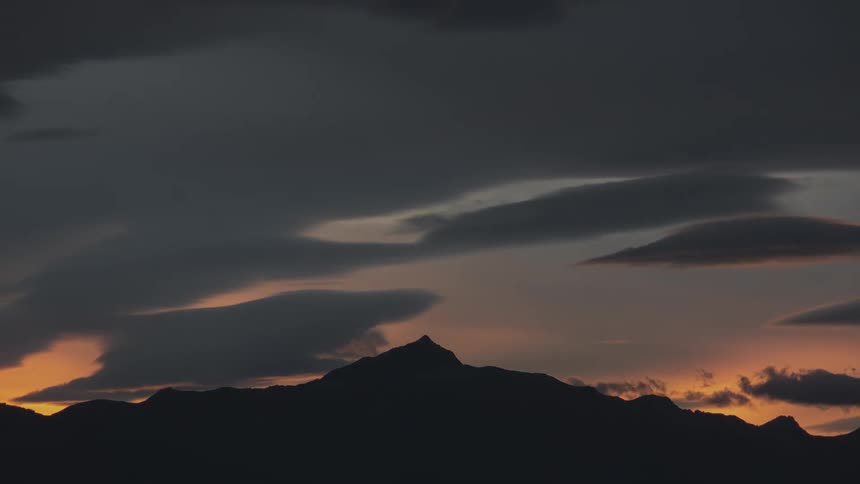 Time lapse of the sun setting behind a mountain