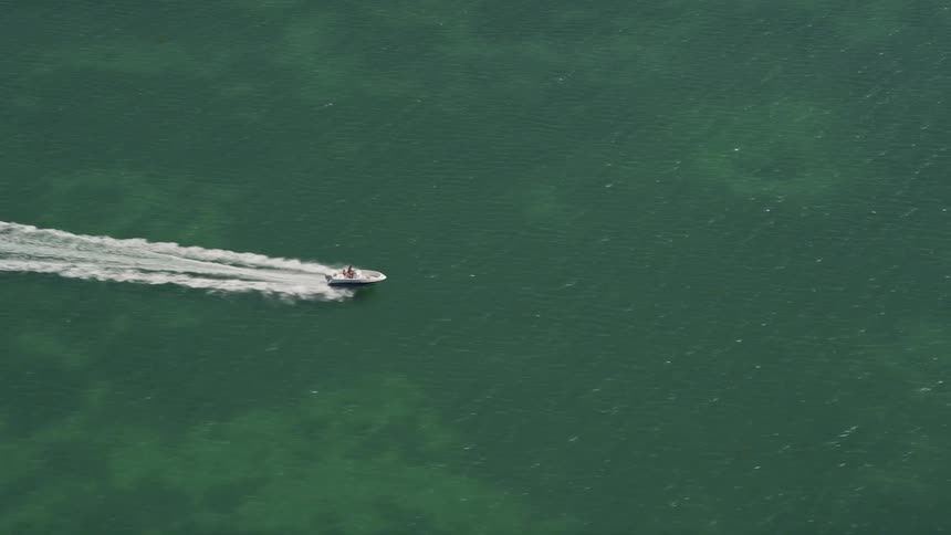 A speedboat tracks across the turquoise waters off the coast of Fat Deer Key in Marathon Florida on a sunny day