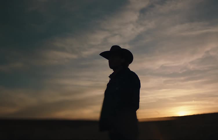 The sun is rising as the man stands outside
