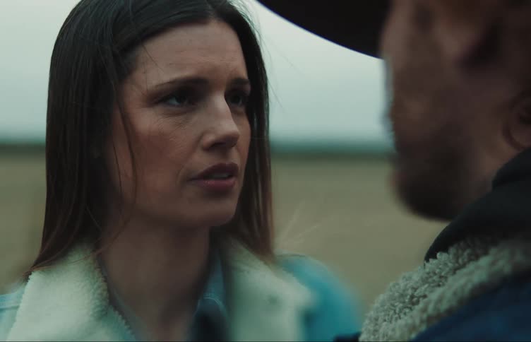 A woman is standing outside looking at a man and she has a concerned look on her face