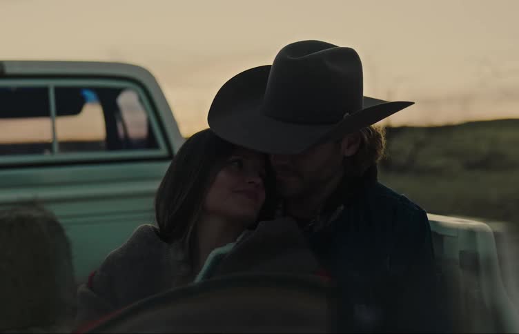 A woman sits on her partners lap in the bed of a pickup