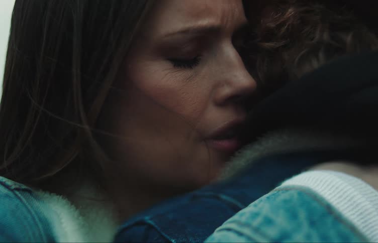 A woman looks at her male companion before giving him a hug