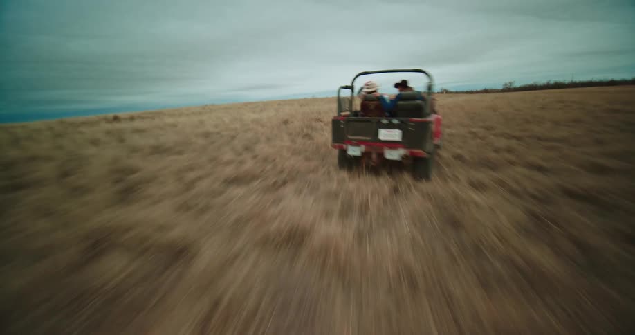 Aerial view of red landcruiser traveling across the brown field