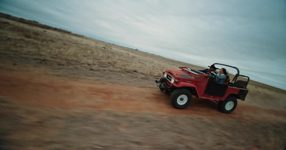 A woman drives a jeep down a dirt road